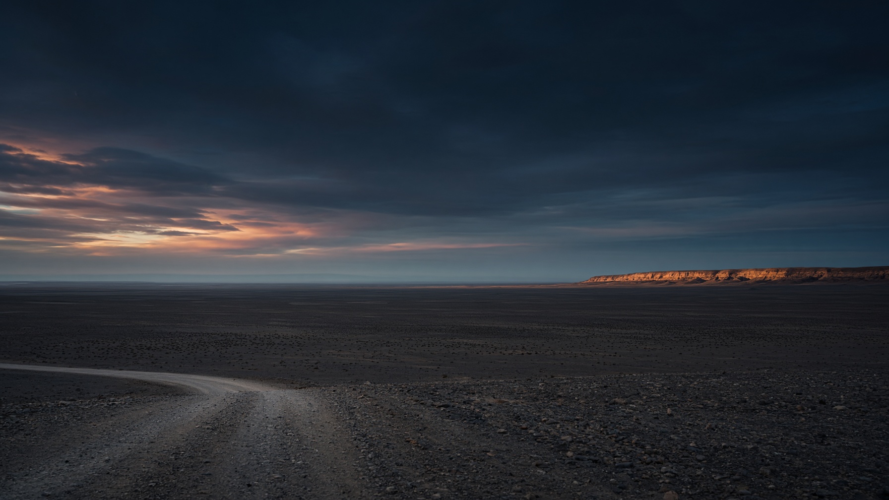 A pale track giving way to open waste at dusk.